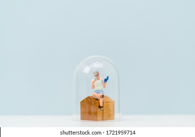 Miniature people : Old man reading the book at home under a glass dome cap stay home safe lives. Stay Home Stay Safe lockdown from coronavirus Covid-19 Pandemic crisis.Healthcare, People, New normal.