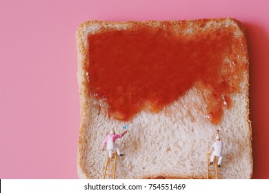 Miniature people painting strawberry jam on bread. - Powered by Shutterstock