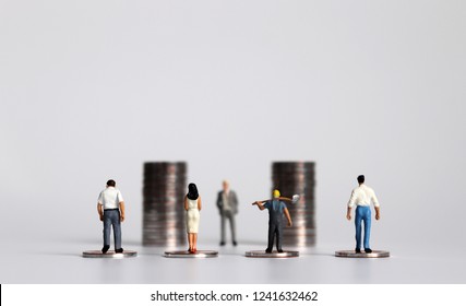 Miniature people with piles of coins. The concept of workers demanding a minimum wage increase.