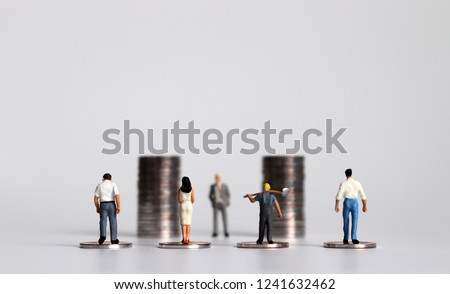 Miniature people with piles of coins. The concept of workers demanding a minimum wage increase.