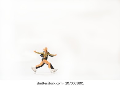 Miniature People As Professional Ice Skater Couple Hugging On White Background. Space For Copy