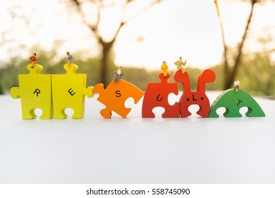 Miniature people with RESULT word jigsaw using as business background.