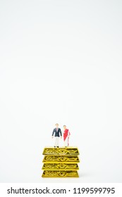 Miniature People :Senior Indian Couple And Rich People Stand On Pile Of Gold Bar  On White Background.Concept For Money, Financial, Business Planning,Gold Business And Rich People In India.