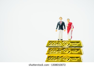 Miniature People :Senior Indian Couple And Rich People Stand On Pile Of Gold Bar On White Background.Concept For Money, Financial, Business Planning,Gold Business And Rich People In India.