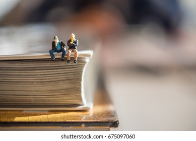  miniature people sitting on the corner of the book. using as education concept - Shutterstock ID 675097060