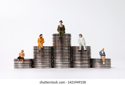 Miniature people sitting on piles of coins. The concept of stratification by income.
