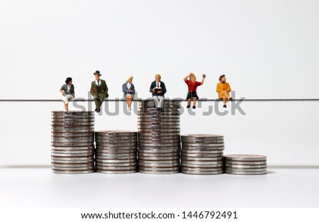 Miniature people sitting side by side with piles of coins of different heights.