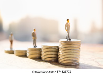 Miniaturleute: Kleine Figur, die auf dem Münzstapel steht. Geld- und Finanzkonzepte.