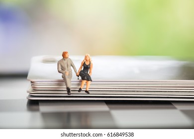 Miniature People: Small Figures Toy Young Couple Sitting And Discuss About Business Deal On Stack Of Credit Cards, Banking Finance Technology, Shopping And E-commerce Concept