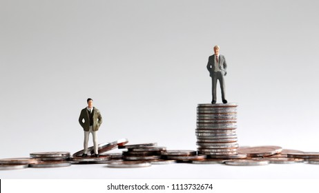 Miniature people standing on a pile of coins. - Shutterstock ID 1113732674