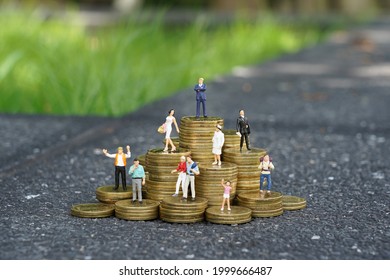 Miniature people standing on pile of coins, financial and money savings concept.