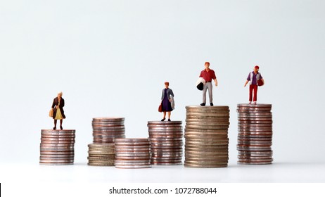 Miniature people standing on piles of different heights of coins. The concept of a growing income gap between individuals. - Shutterstock ID 1072788044