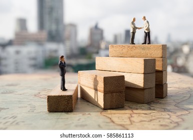 Miniature people: Successive business concept. Businessman thinking on first step of wood stair and two businessmen shaking hands on top step with modern city background.
