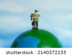 Miniature people toy figure photography. Family reunion day concept. Father hugging his wife and daughter above earth globe. Image photo