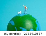 Miniature people toy figure photography. International kids day concept. A kid playing with dog above earth globe, isolated on blue background. Image photo