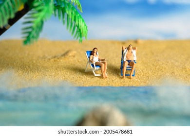 Miniature people toy figure photography. Men and girl couple relaxing on beach chair when daylight at seaside. Image photo - Shutterstock ID 2005478681