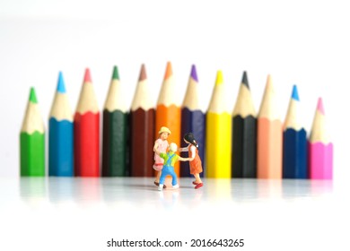 Miniature People Toy Figure Photography. Drawing Class Concept. A Group Of Kids Playing On Colorful Pencil, Isolated On White Background. Image Photo