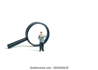 Miniature People Toy Figure Photography. A Men Student Standing In Front Of Magnifier Glass, Isolated On White Background. Image Photo