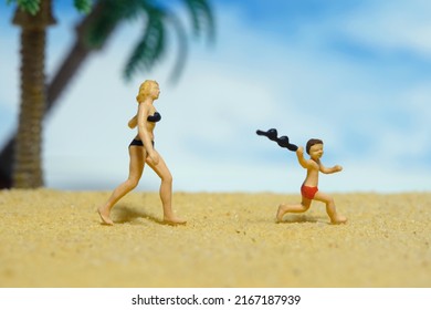 Miniature people toy figure photography. Brother and sister having fun running on the beach. Beautiful bright beach landscape background. Image photo