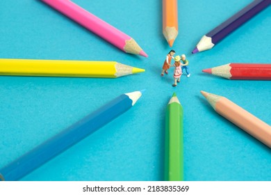 Miniature People Toy Figure Photography. Drawing Class Concept. A Group Of Kids Playing On Colorful Pencil, Isolated On Blue Background. Image Photo