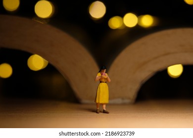 Miniature People Toy Figure Photography. A Girl Reading A Book At Night With Bokeh Defocused Light Lamp, Bed Time Routine Before Sleep. Image Photo