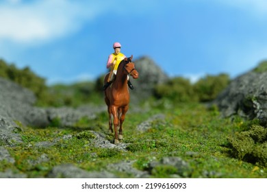 Miniature People Toy Figure Photography. A Jockey Man Riding Horse At Mountain Hill For Training. Image Photo