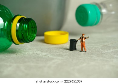 Miniature people toy figure photography. Cleaning workers walk among plastic drink bottles scattered on the floor near the trash can. Image photo - Shutterstock ID 2229651359