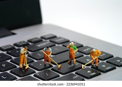 Miniature people toy figure photography. Group of sweeper workers cleaning notebook laptop keyboard using broom, brush. Isolated on white background. Image photo - Shutterstock ID 2236941011