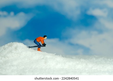 Miniature people toy figure photography. Winter sport. A male downhill ski racer slides down from the top of the hill. Image photo
