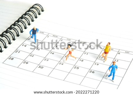 Miniature people toy figure photography. Running daily routine concept. A young men and women runner jogging above calendar planner schedule, isolated on white background. Image photo