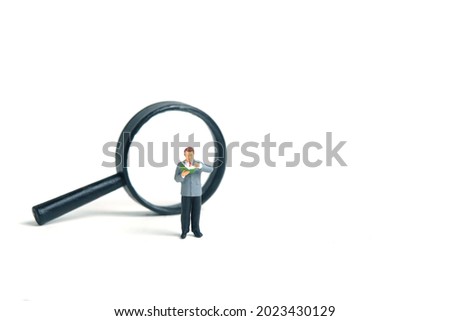 Miniature people toy figure photography. A men student standing in front of magnifier glass, isolated on white background. Image photo
