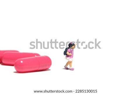 Miniature people toy figure photography. A girl student standing in front of medical drug pill. Isolated on white background. Image photo