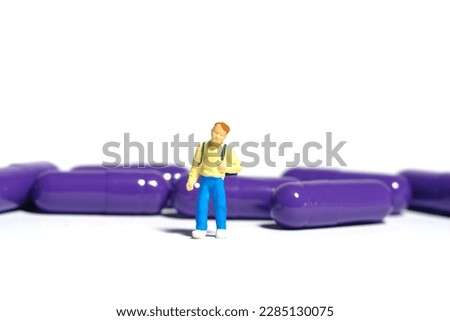 Miniature people toy figure photography. A boy student standing in front of medical drug pill. Isolated on white background. Image photo