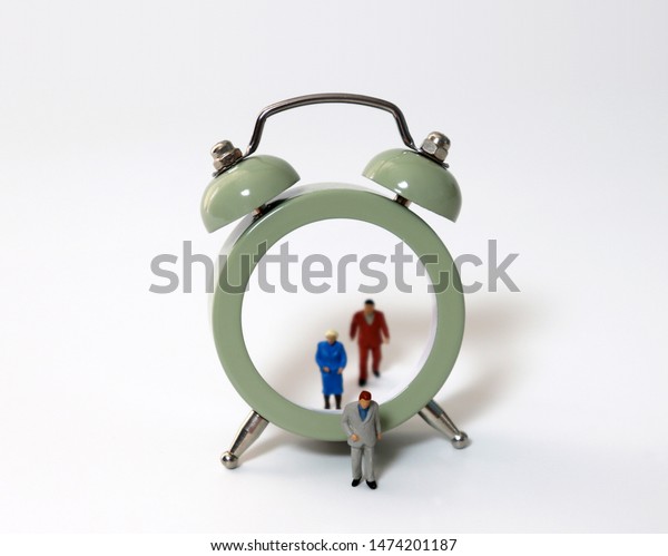 Miniature people walking out of the clock. The concept of old age and retirement.