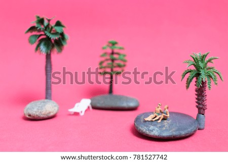 Miniature people wearing swimsuit relaxing on the rock with pink background , Valentine's day concept