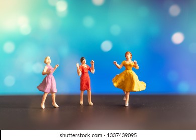 Miniature people , Woman in colored dress  dancing against bokeh background