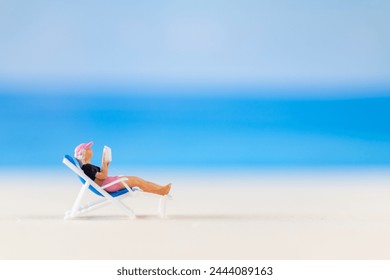 Miniature people , a woman relaxing on a deck chair and reading a book and copy space for text - Powered by Shutterstock