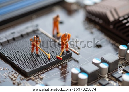 Miniature People: Worker cleaning professional repairman holding a cleaning brush inside old personal computer. CPU cleaning and maintenance concept, close up view.
