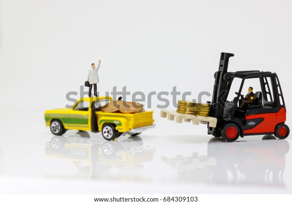 miniature people workers on money\
coin stack with Pickup truck. business investment concept.\
\

