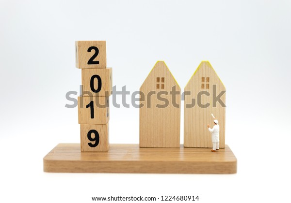 Miniature\
people: Workers are painting color the home and wood block 2019.\
Image use for Construction business\
concept.