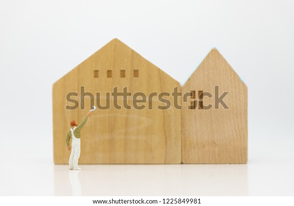 Miniature people: Workers\
are painting color the home. Image use for Construction business\
concept.