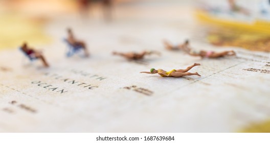 Miniature People : Young In Swimsuit And Friends Swiming On World Map. Image Use For Holiday, Vacation Concept.