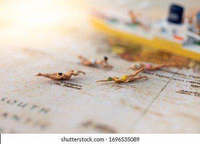 Miniature People : Young In Swimsuit And Friends Swiming On World Map. Image Use For Holiday, Vacation Concept.