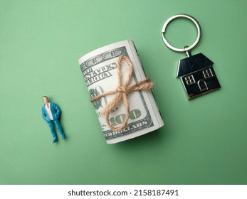 Miniature people,banknotes and hosue keychain on a green background. The concept of buy new home.