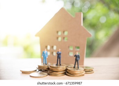 Miniature people,Real estate investment. House and coins on table. - Shutterstock ID 671359987