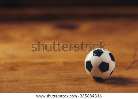 Miniature plastic soccer ball on wooden table with copy space, retro toned selective focus