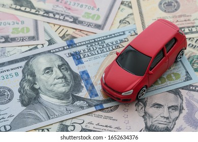 Miniature Red Car Model On US Dollar Banknotes Bill Background With Copy Space. Business, Finance Or Budget Plan Money Saving For Buying A New Car And Auto Insurance Concept.