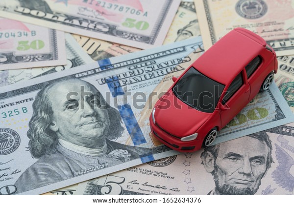 Miniature red car\
model on US dollar banknotes bill background with copy space.\
Business, finance or budget plan money saving for buying a new car\
and auto insurance\
concept.