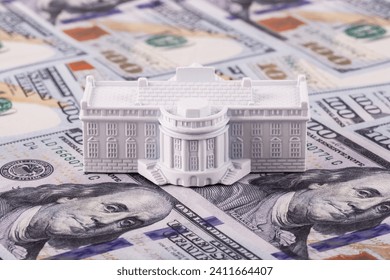 A miniature residence of the President of the United States, the White House, against the backdrop of 100 US dollar bills. - Powered by Shutterstock