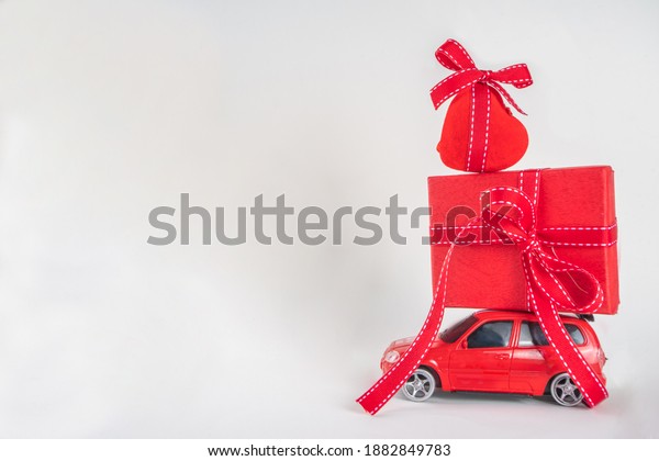 Miniature retro toy red car carrying red heart
decor, on white background copy space. Valentine day concept,
greeting card
background
